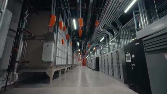 Buffer tanks on the mechanical floor. The wheels overhead are isolation valves with extended chain pulls; the boxy units in the back are the traditional CRAC air handlers, still doing useful work alongside the new liquid loop.